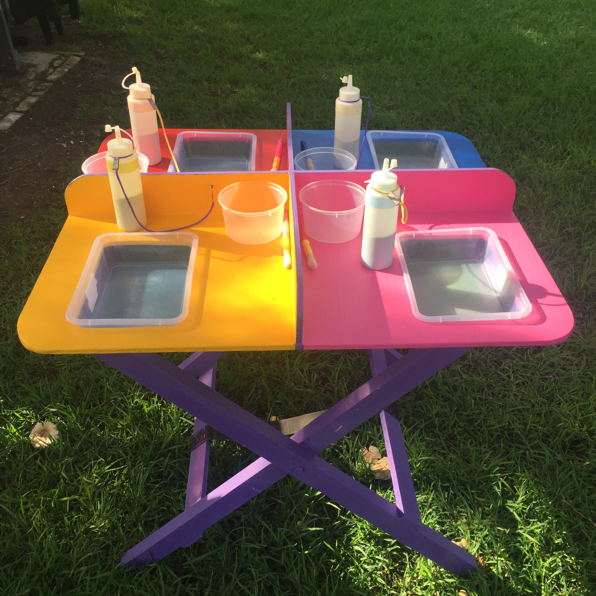 Colourful folding SandArt hire table set up with sand trays, bottles and tools